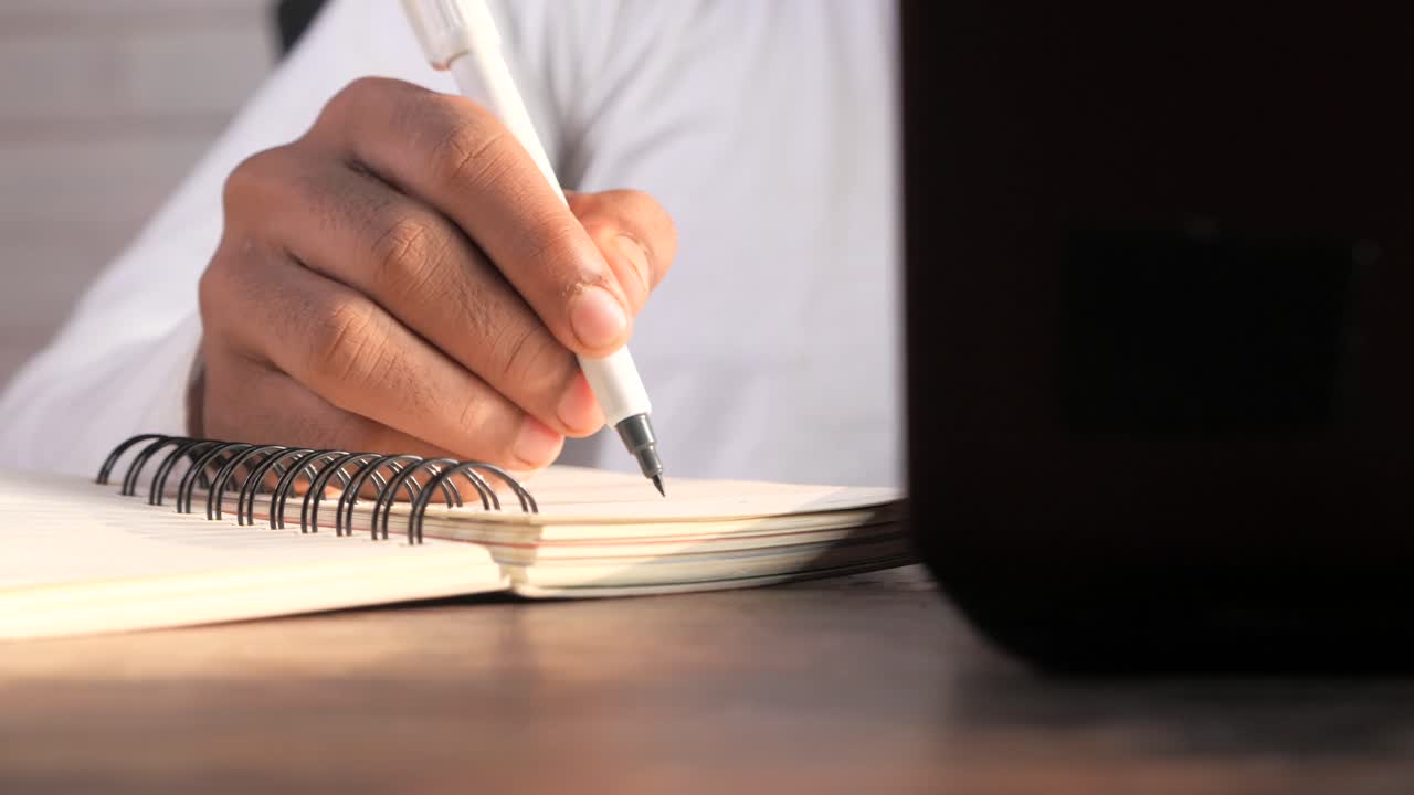 Close-up of a Person's Hand Writing in a Notebook