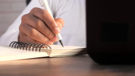 close-up of a person's hand writing in a notebook