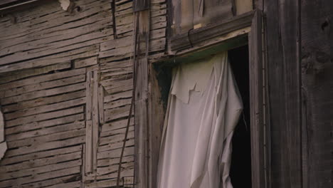 post apocalyptic abandoned home strewn together with wood plank boards nails and sheet curtain