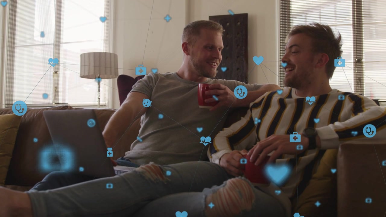 Laptop user using trackpad leaning to partner with red mug sharing laughing blue icons showing tech