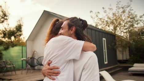 close-up shooting: a girl jumps on her boyfriend and hugs him near the sunbeds by the pool. rest in the country house