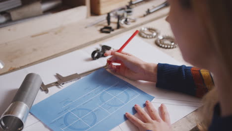 close up of female engineer in workshop making notes on plan for handmade bicycle