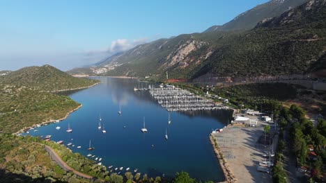 aerial ascend establishing of kas bay in antalya, turkey, with serene blue waters surrounded by green hills and coastal roads, boats line docks in calm water