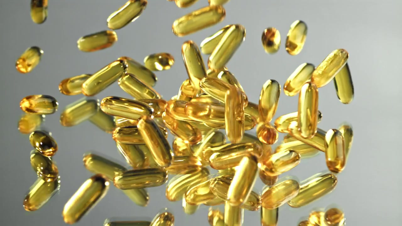 Capsule softgel di Omega 3 dorate che cadono al rallentatore