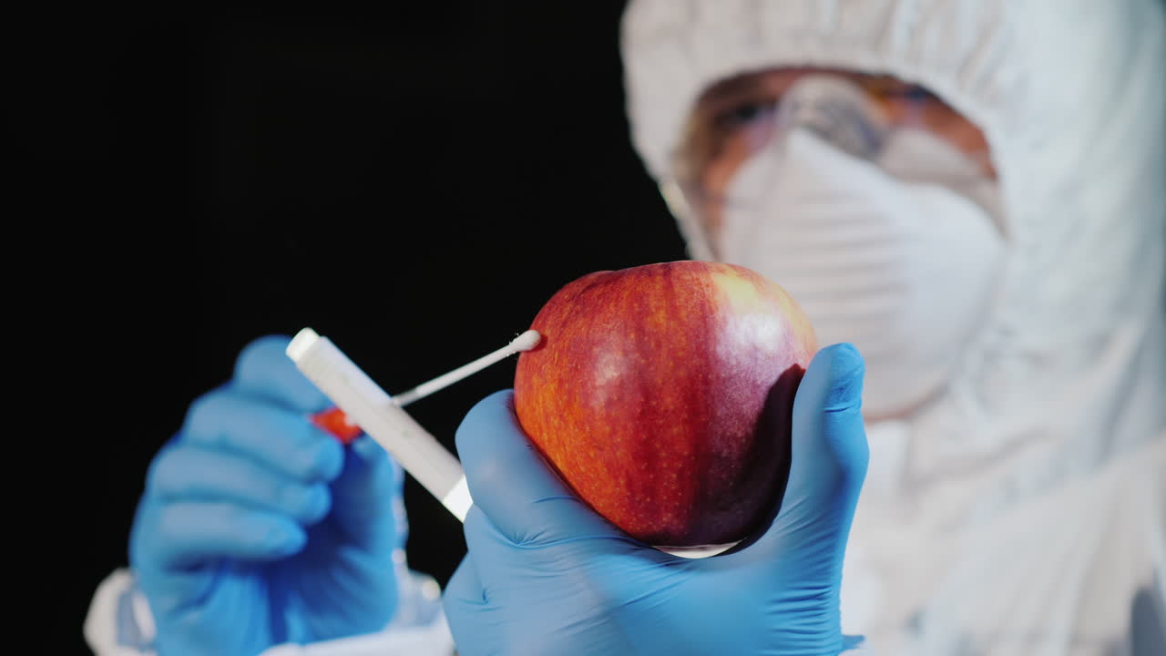 un hombre con ropa protectora y guantes toma una muestra de una manzana grande 1