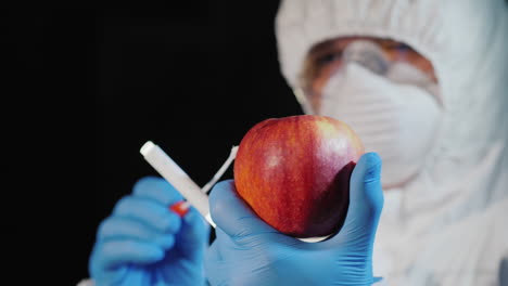 a man in protective clothing and gloves takes a smear from a large apple 1