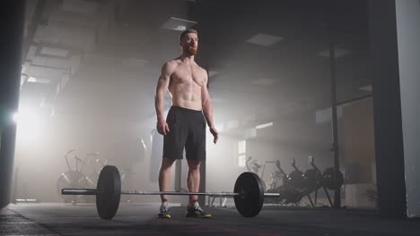 athletic beautiful man does overhead deadlift with a barbell in the gym. gorgeous male professional bodybuilder workout weight lift exercises in the authentic fit training facility