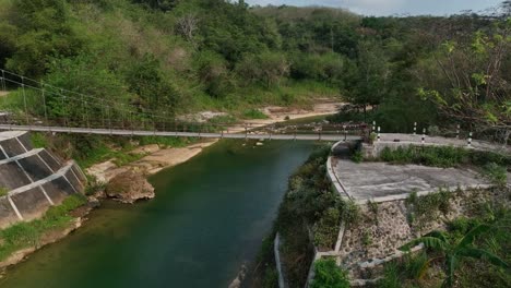 Drone-Pasando-Sobre-El-Puente-Gantung-Wanagama-Al-Comienzo-De-La-Estación-Seca---Con-Follaje-A-Juego-Para-La-Condición-Seca