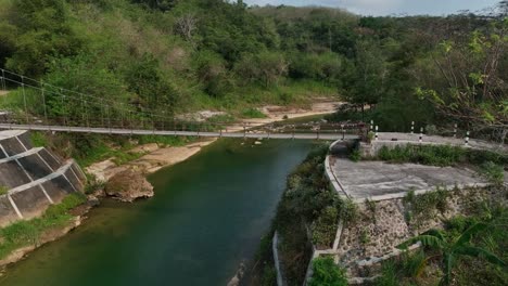 avión no tripulado que pasa sobre el puente de gantung wanagama al comienzo de la estación seca - con follaje a juego para la condición seca