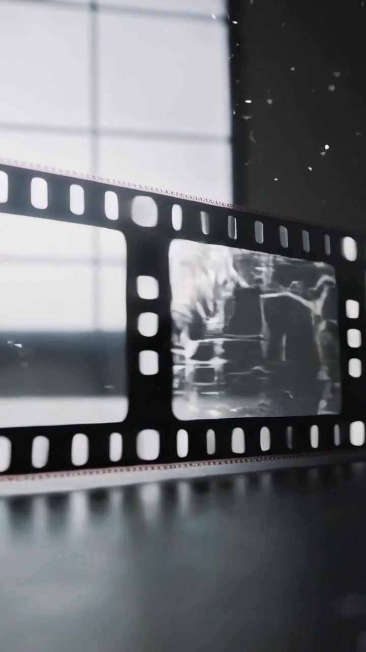 Vídeo vertical: Câmera deslizando revelando uma tira de filme 35mm sobre a mesa perto da janela, para inspecionar danos.
