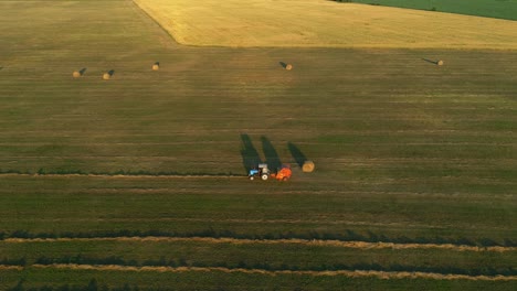 aerial view tractor baling machine making silage bales on farmland, haystack