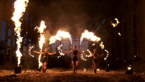 professional fire show in the old hangar of the aircraft show professional circus artists three women in leather suits and a man with two flamethrowers.