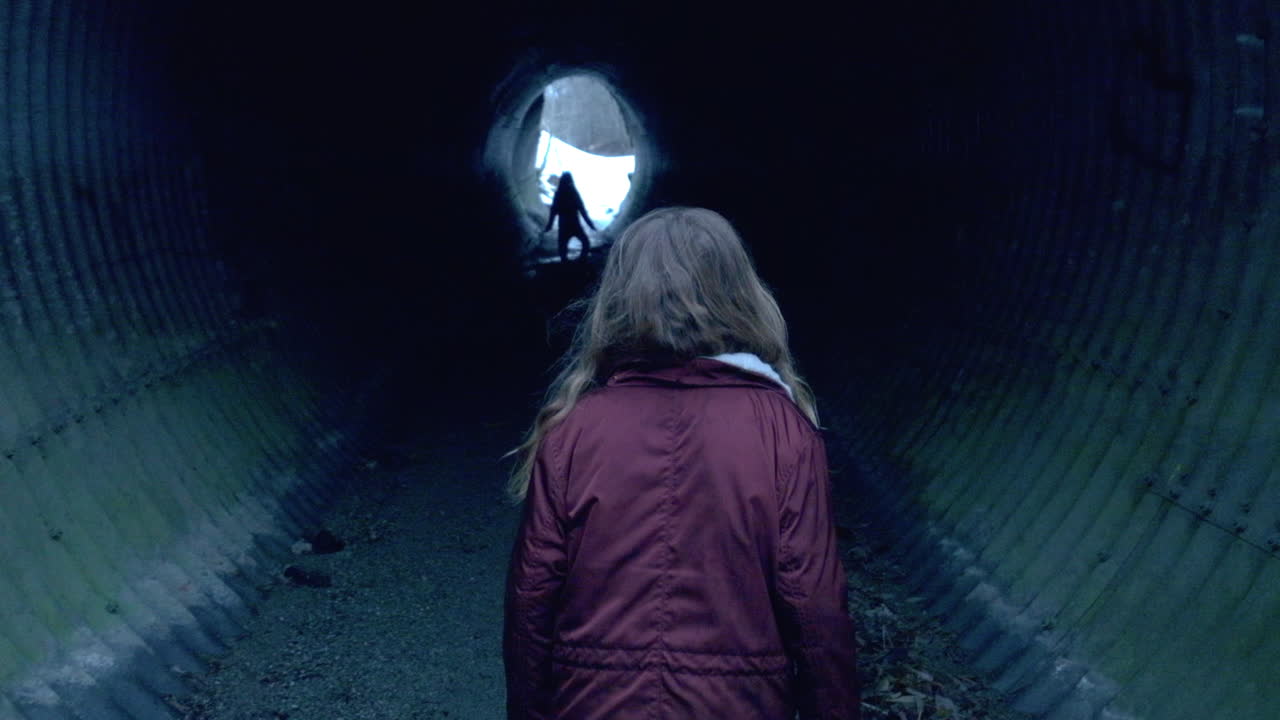 A little girl walking in slow motion into a dark underground tunnel feeling scared