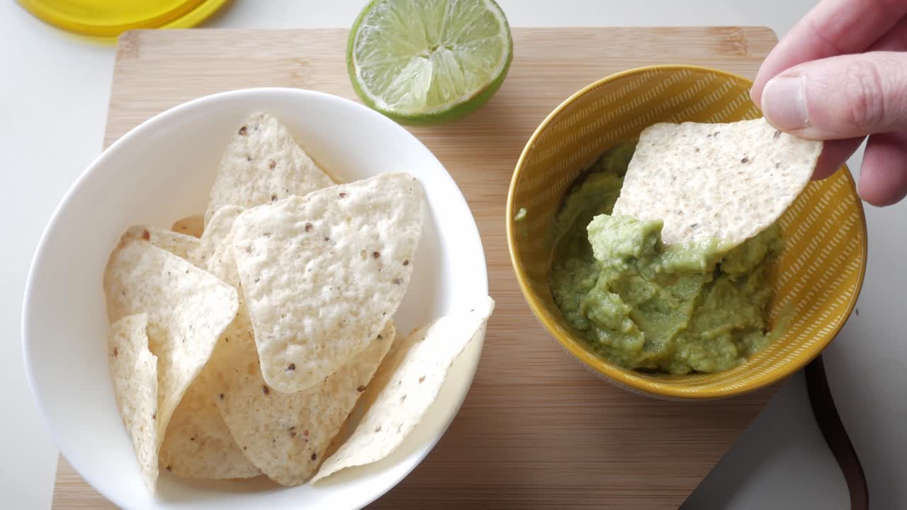Guacamole and tortilla chips served with lime in a casual indoor kitchen setting