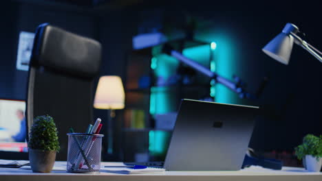 office desk filled with business items in empty home interior with tv left open