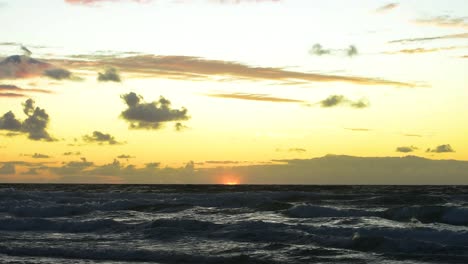 amanecer sereno sobre las olas del océano pacífico con un cielo amarillo y naranja brillante