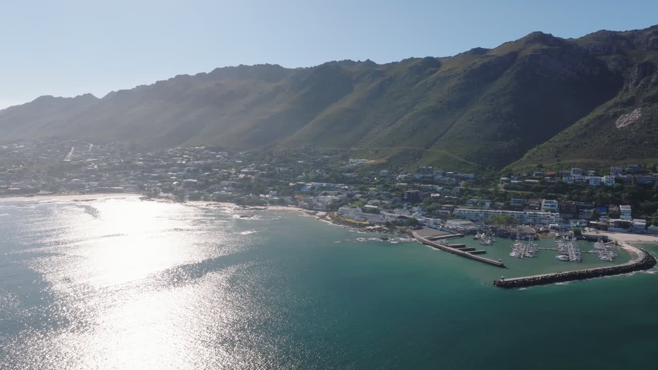남아프리카 공화국의 고든스 베이 (gordons bay) 의 물 표면에 반사되는 태양. 마리나와 주차 요트와 보트가 있는 항구.