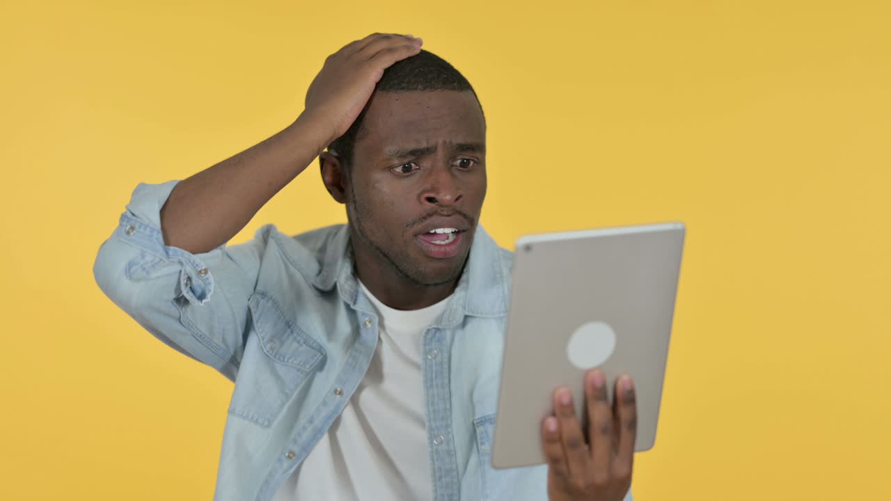 Young African Man Reacting to Loss on Tablet, Yellow Background