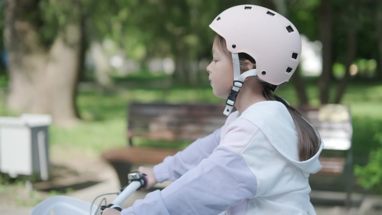 Young Girl Wearing Helmet on Bicycle in Park