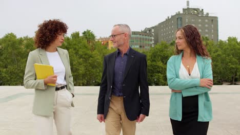three business people walking and talking outdoors