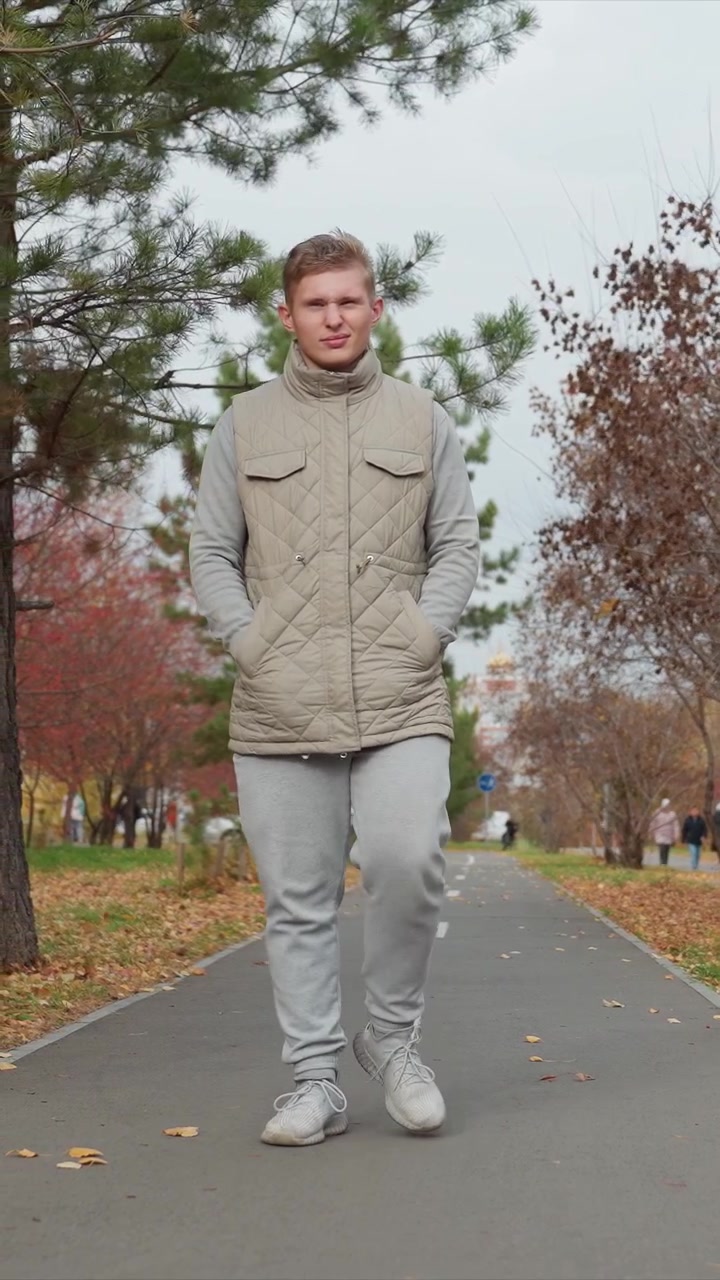 Giovane uomo che passeggia su un sentiero in un parco autunnale