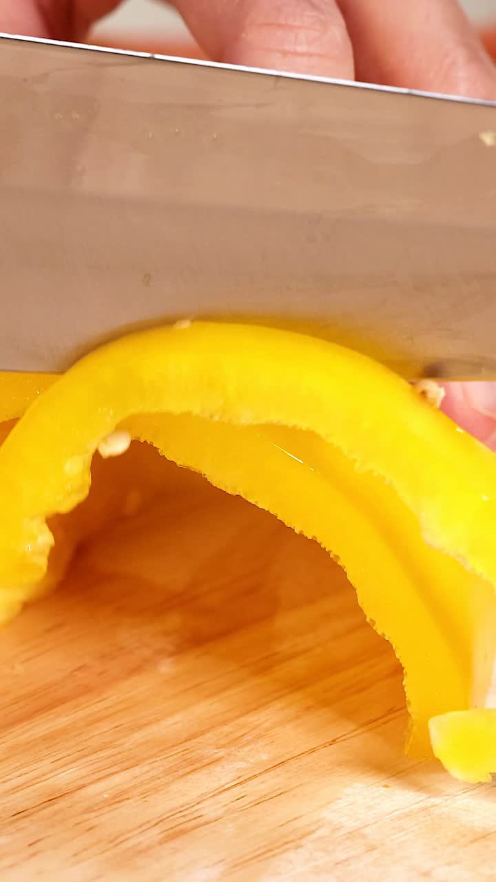 manos cortando pimientos amarillos en una tabla de madera
