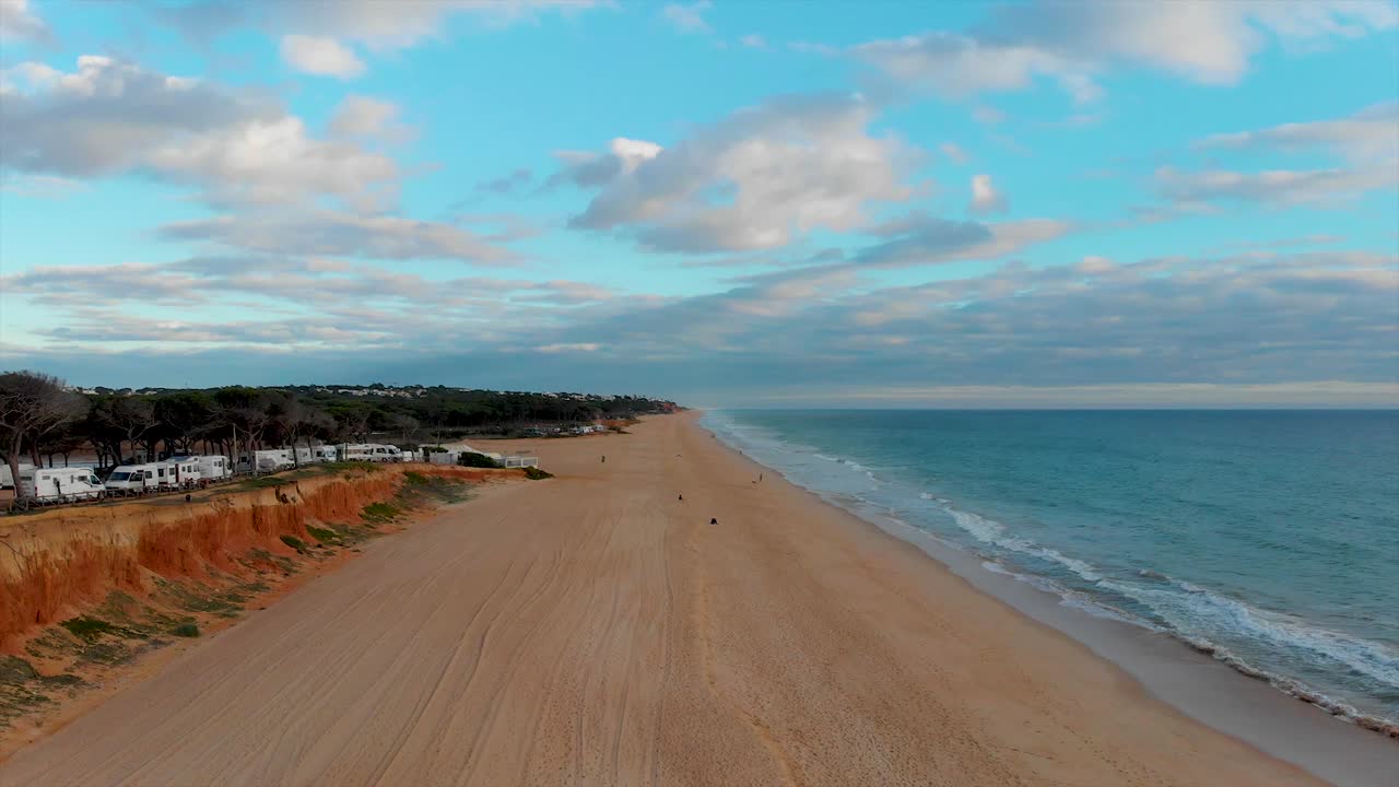 vista aérea de una playa en un día nublado con un acantilado y pinos