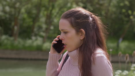 mujer estresada o enojada al aire libre con preocupaciones financieras sobre el costo de la vida crisis deuda y pago de facturas hablando por teléfono móvil caminando por el río 3
