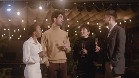 group of four happy multiethnic friends toasting and drinking champagne at new year's eve party