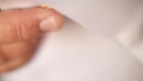 close up on man wearing and adjusting david star shaped golden cufflink on white shirt