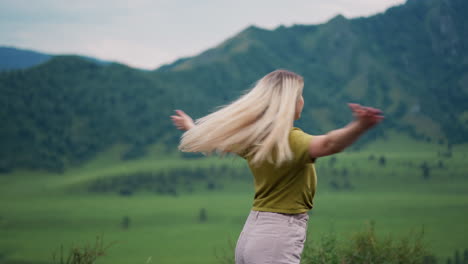 Happy-woman-with-loose-hair-spins-around-in-mountain-valley