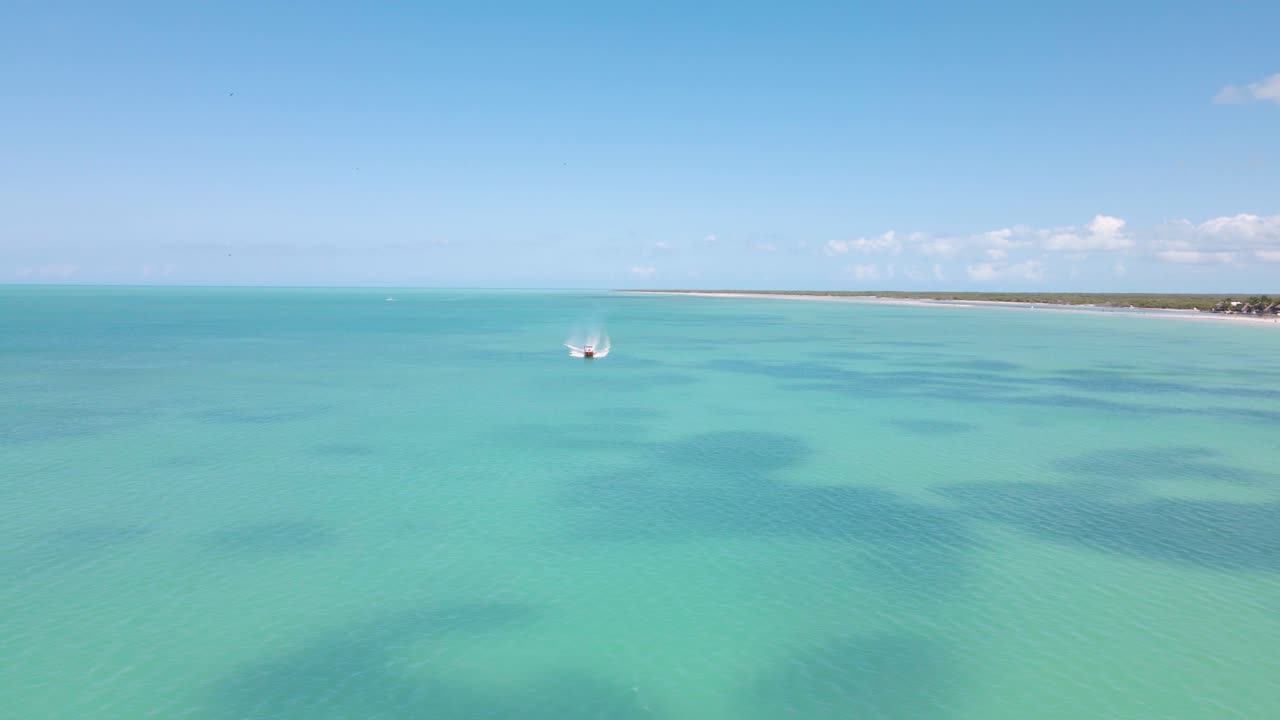 disparo de dron de gran angular acercándose a un barco que pasa por el marco conduciendo en las aguas cristalinas frente a la costa de la isla tropical de holbox en méxico filmada en 4k