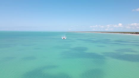 Weitwinkel-Drohnenaufnahme,-Die-Sich-Einem-Boot-Nähert,-Das-Am-Rahmen-Vorbeifährt-Und-Auf-Dem-Kristallklaren-Blauen-Wasser-Vor-Der-Küste-Der-Tropischen-Insel-Holbox-In-Mexiko-Fährt,-Aufgenommen-In-4k