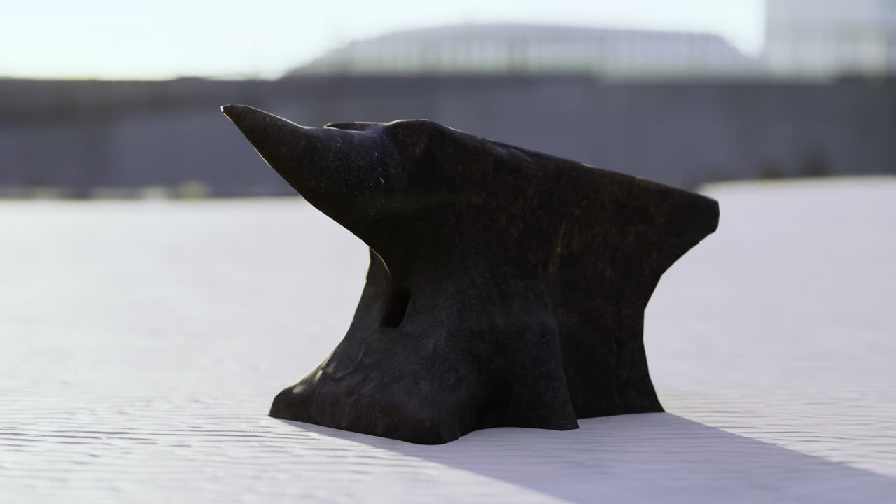 Blacksmiths anvil resting on a white surface under bright sunlight