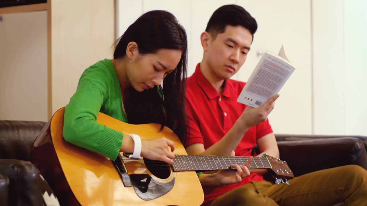 Pasangan bermain gitar di ruang tamu