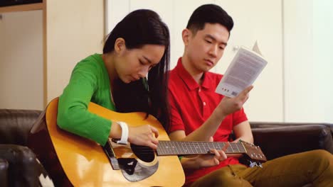Couple-playing-guitar-in-living-room