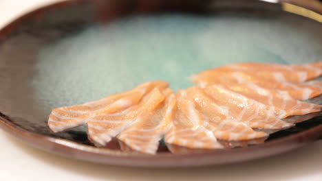 chef carefully lying the thinly sliced salmon sashimi on a plate