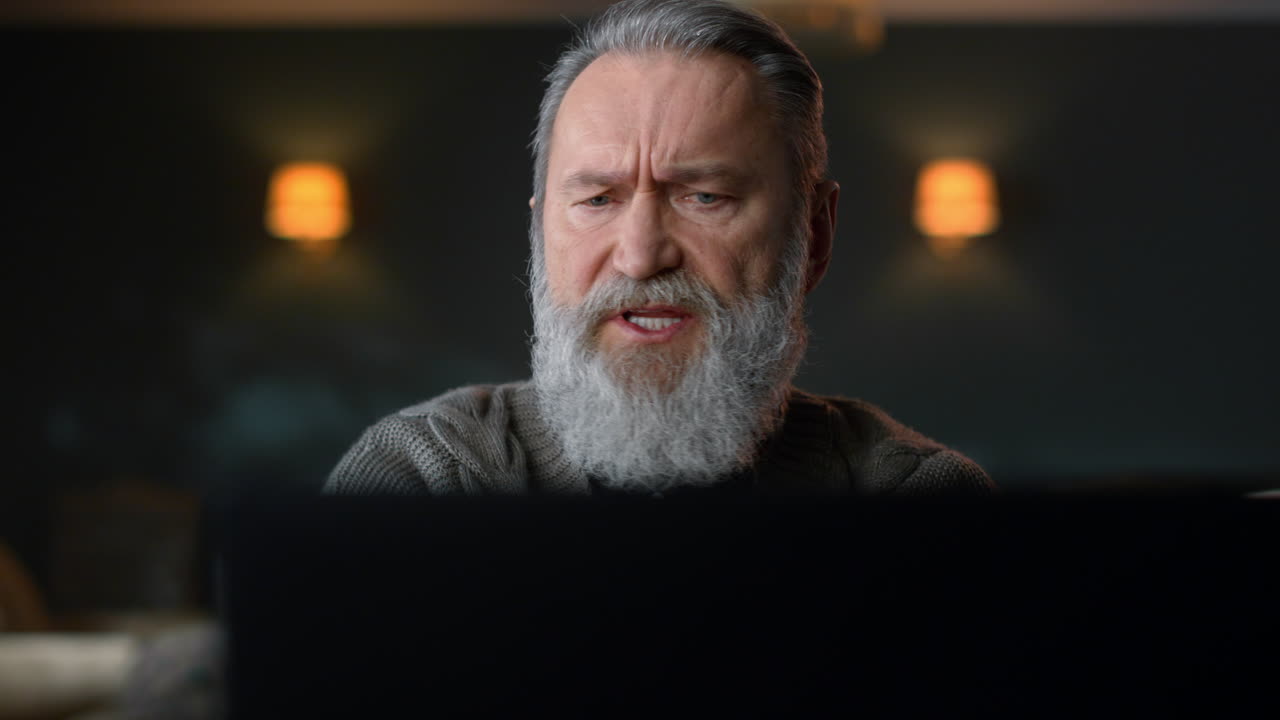 Old business man using laptop computer for video call in luxury living room.