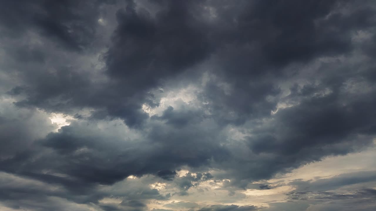 Timelapse of dramatic dark storm clouds moving fast with sunlight peeking through. Perfect for cinematic skies, weather transitions and mood-setting B-roll footage.