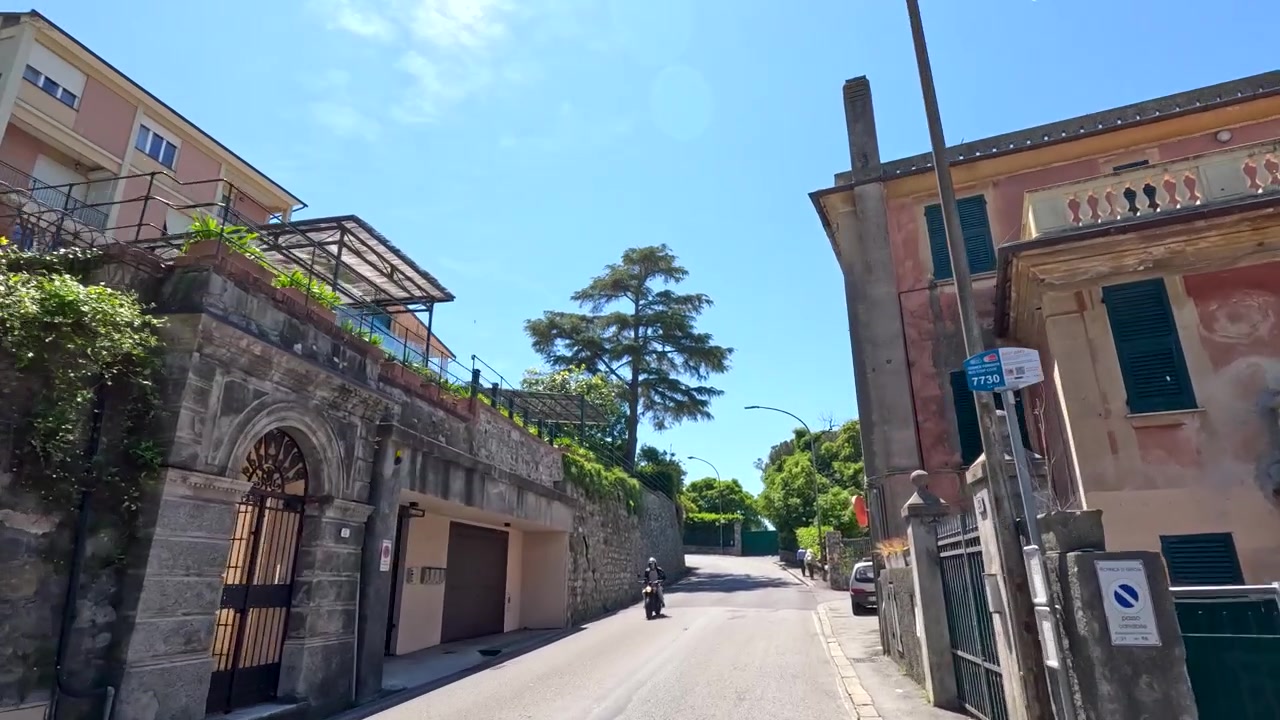Una ripresa in movimento dal basso si sposta lungo una strada stretta fiancheggiata da architettura tradizionale mediterranea
