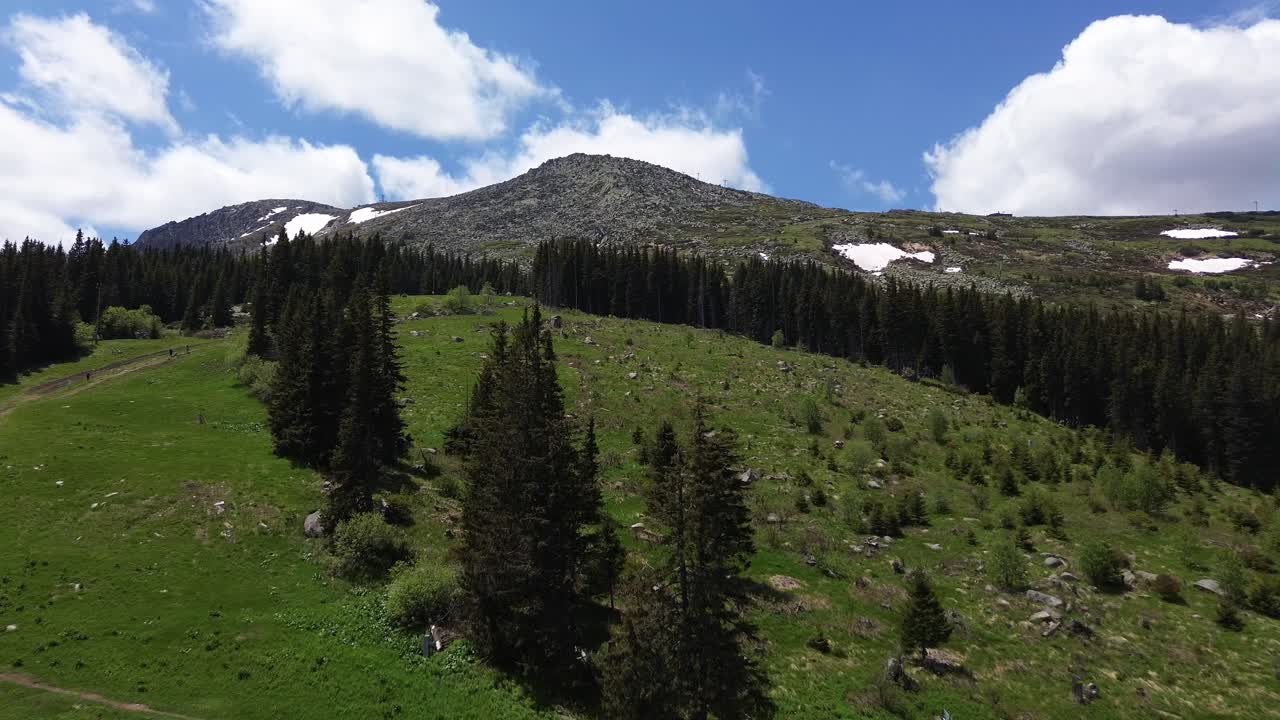 dron volando a través de un camino de tierra de montaña con turistas