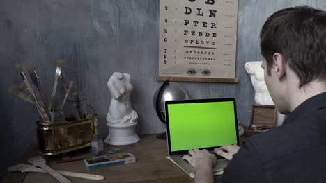 man working on a laptop in an artistic workspace