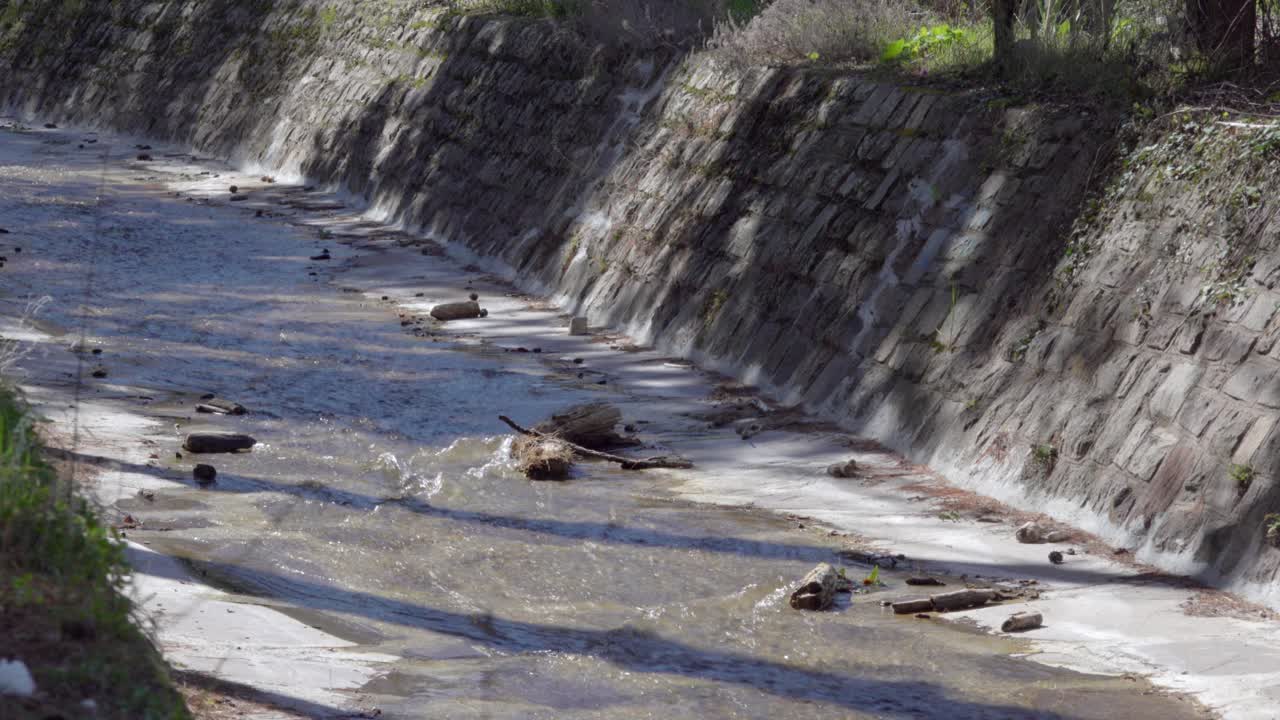 A trickle flows along a canal during a warm and sunny day in spring