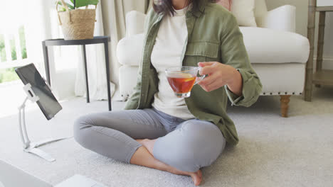 happy asian woman drinking tea, using laptop and tablet in bedroom, in slow motion