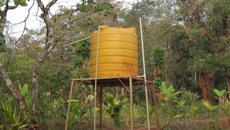 depósito de agua de color amarillo brillante en la torre con fondo de bosque verde