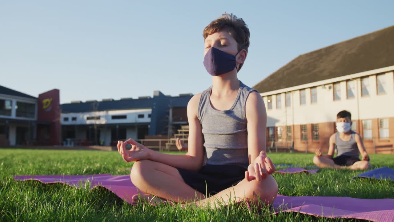 niño con máscara facial realizando yoga en el jardín