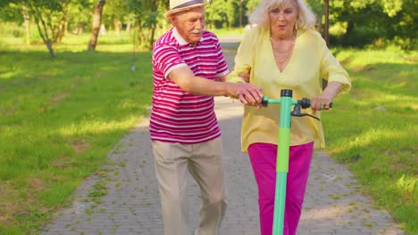 senior old stylish tourists grandmother, grandfather using electric scooter enjoying learning ride