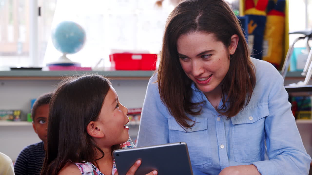 maestra y niña en la escuela primaria usando una tableta