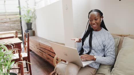 Happy-african-american-woman-using-laptop-for-video-call-sitting-in-coffee-shop,-slow-motion