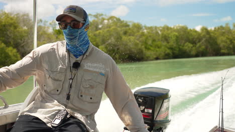 Sun-Safe-Fisherman-In-Hat-And-Sunglasses-Piloting-Small-Boat-Along-Australian-Creek-On-Sunny-Day,-4K